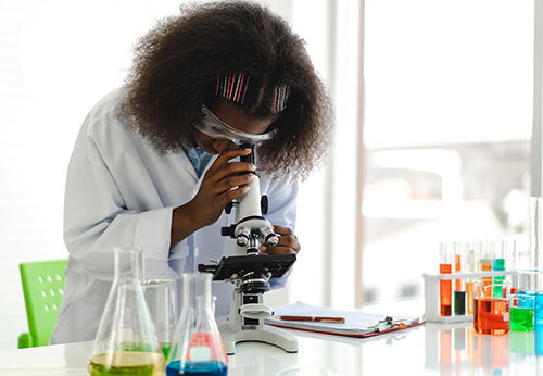 Female looking through microscope in lab.