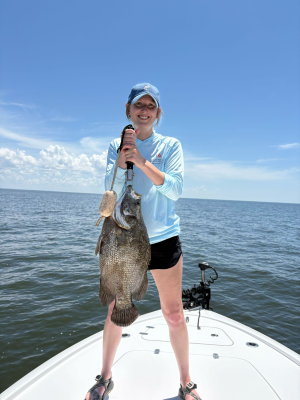 woman standing on the bow of a boat weighing a very large fish
