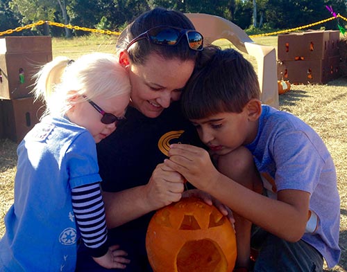 Mom with two kids holding pumpkin.