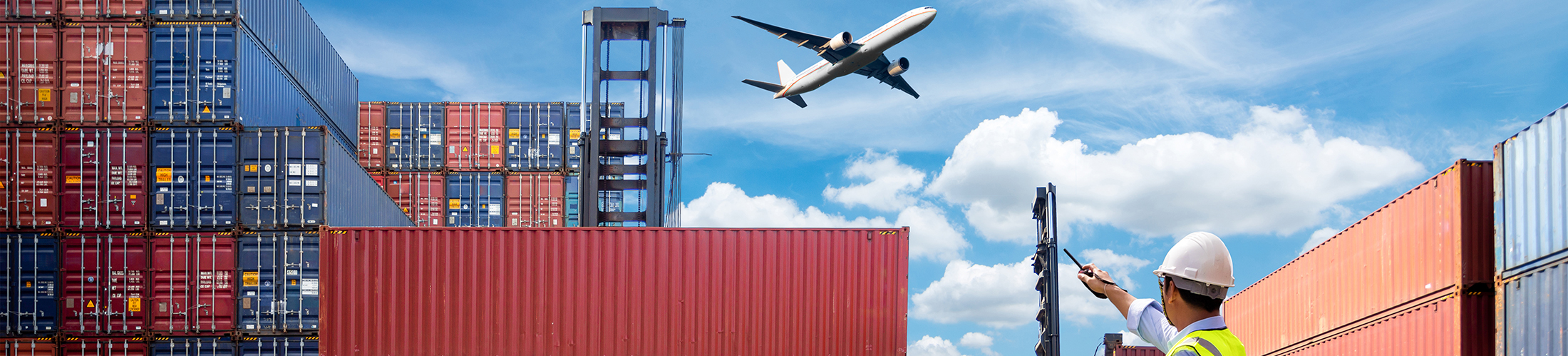 Man at container port pointing to airplane in the sky.