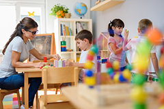 Teacher working with students in class with building blocks.