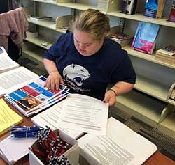 PASSAGE USA Emily working at desk sorting papers.