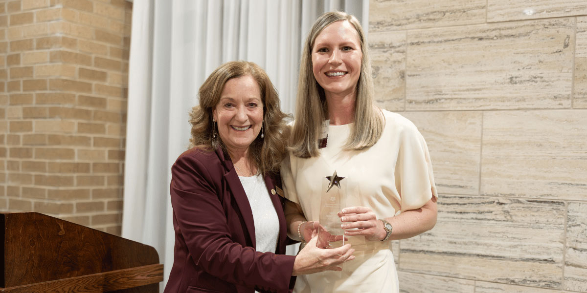 woman with blonde hair receives award from a woman with brown hair data-lightbox='featured'