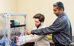 Professor pointing to machine in box.