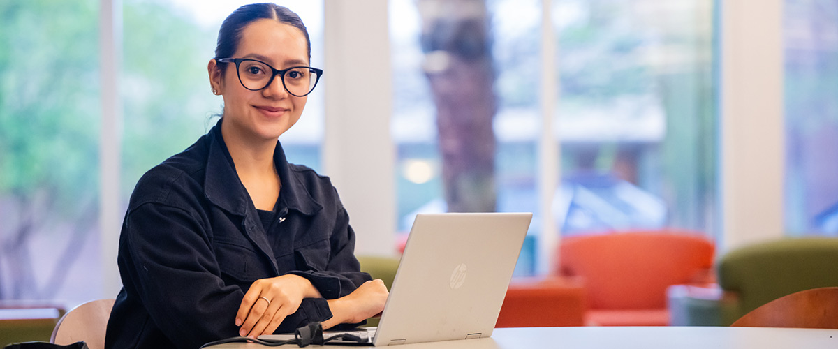 Master of Accounting student with glasses at table with laptop.