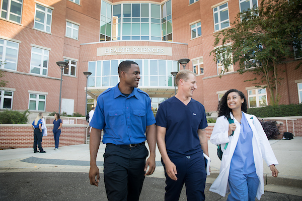 Three allied health stdent walking out of building.