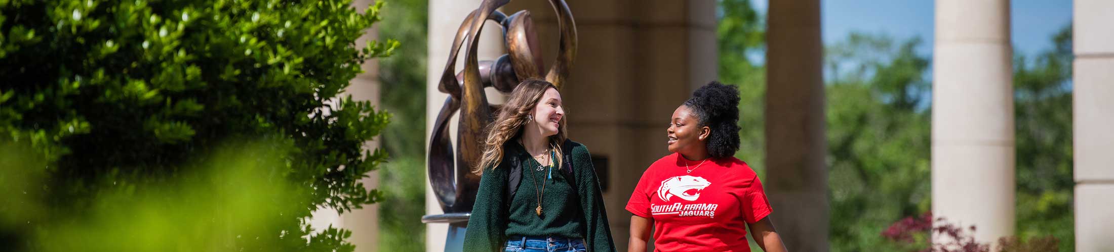 Two students talking and walking outside of Moulton Tower on campus.