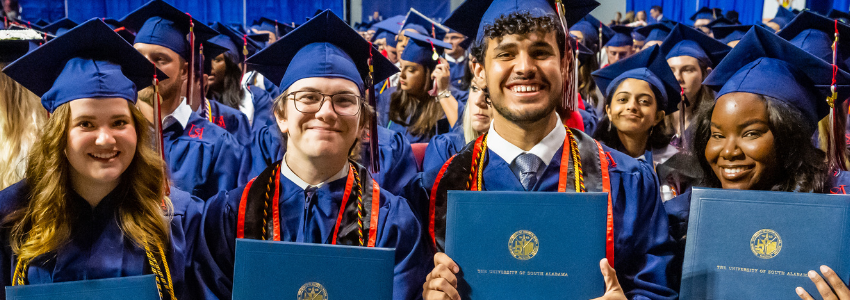 Four grads holding their diplomas.