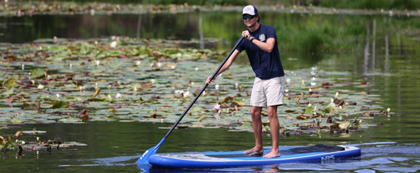 Student paddle boarding on water on campus.