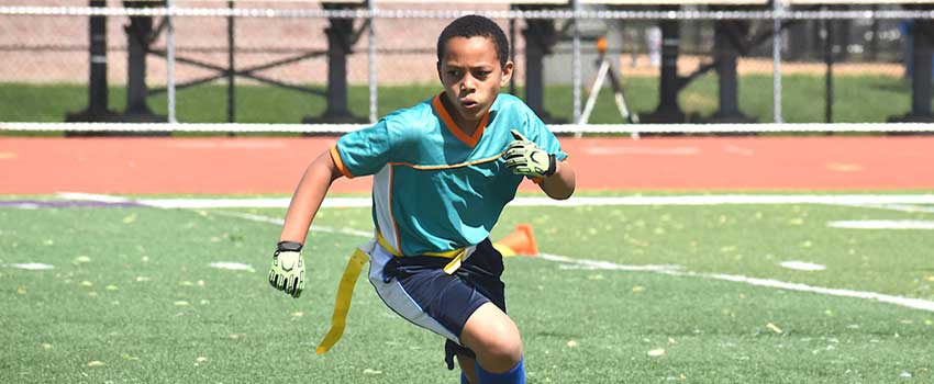 Young boy running playing flag football.