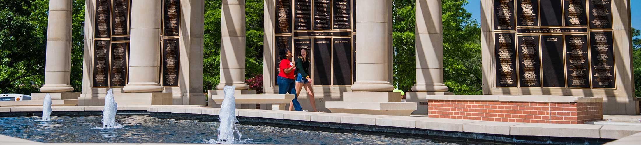 Students walking in front of the Alumni Wall.