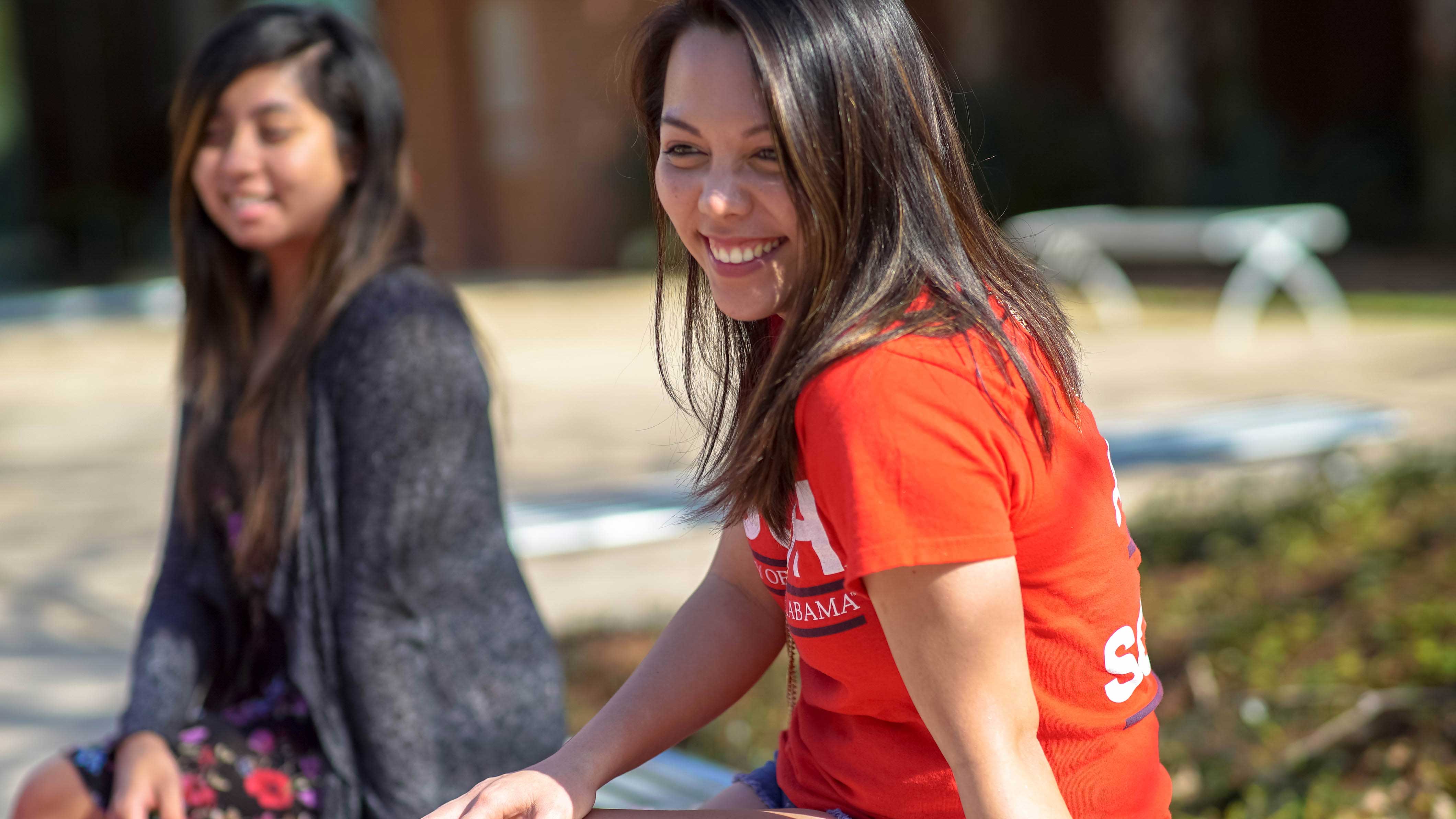 Two students sitting outside smiling