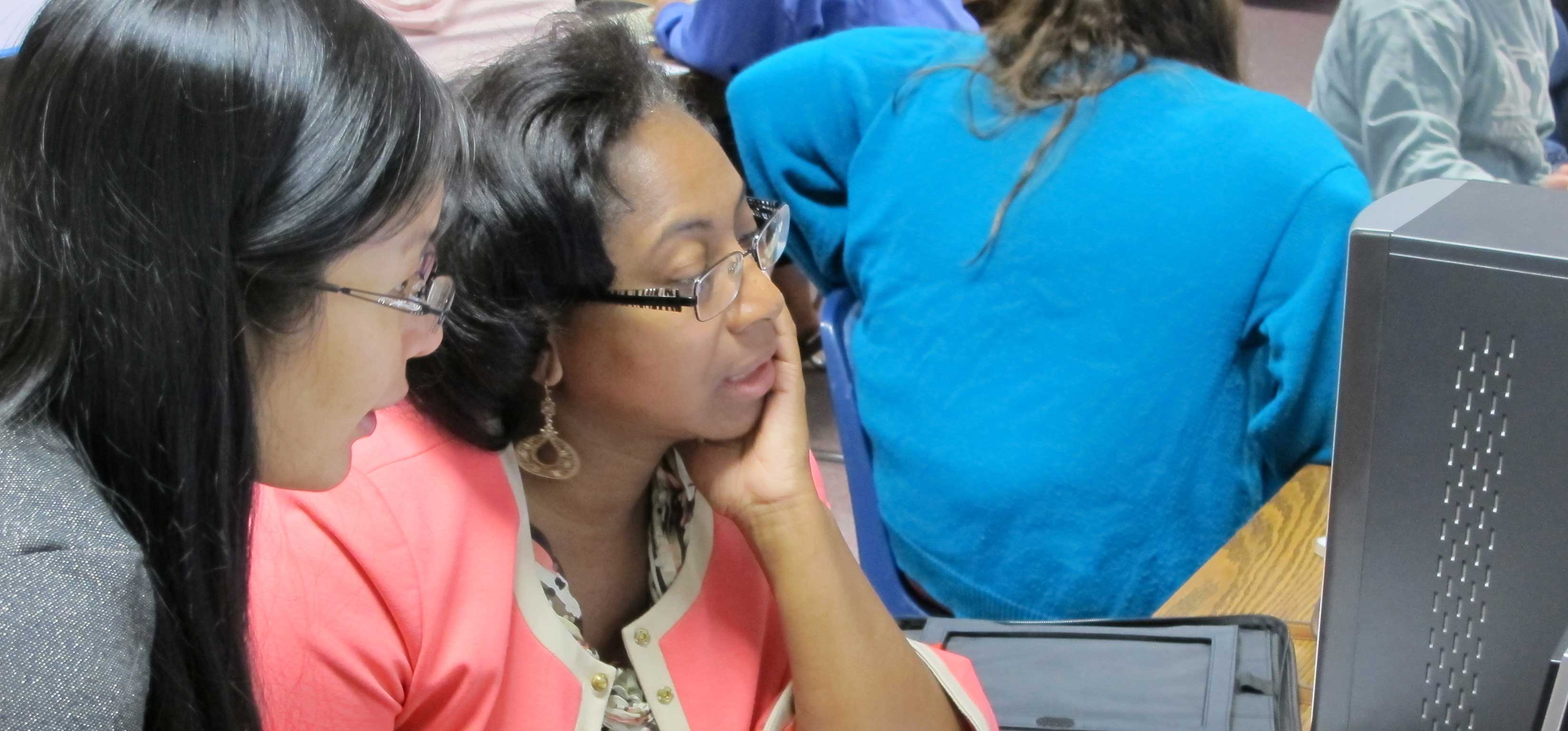 Two women working at computer.