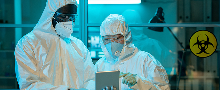 Two people in hazmat suits in lab.