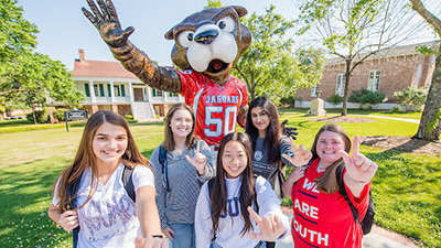 Five students holding up J sign for Jaguars in front of the Southpaw statue.