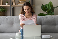 Woman looking at paper sitting on couch